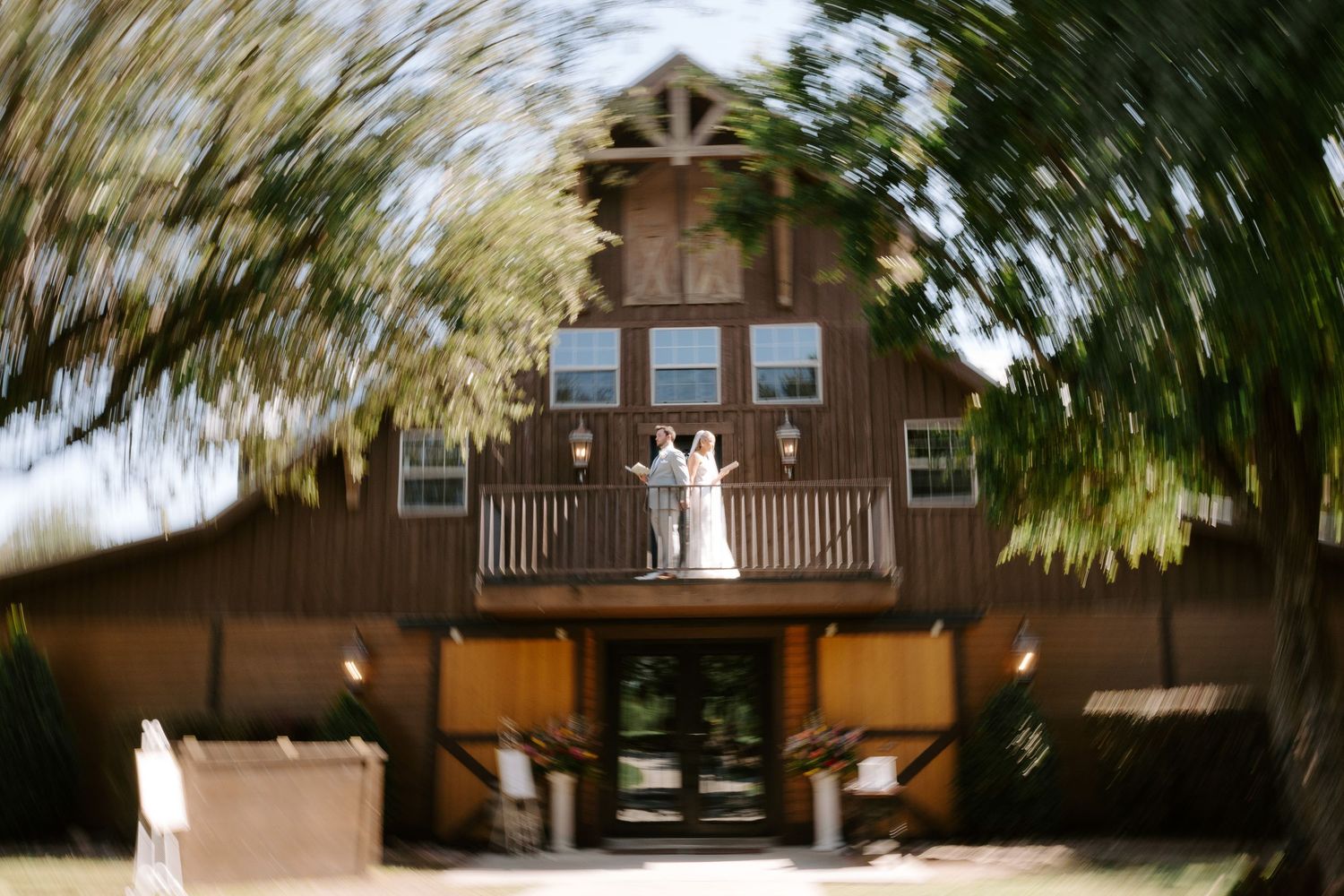 A dreamy motion-blur photo of a rustic barn wedding venue with people on the balcony.