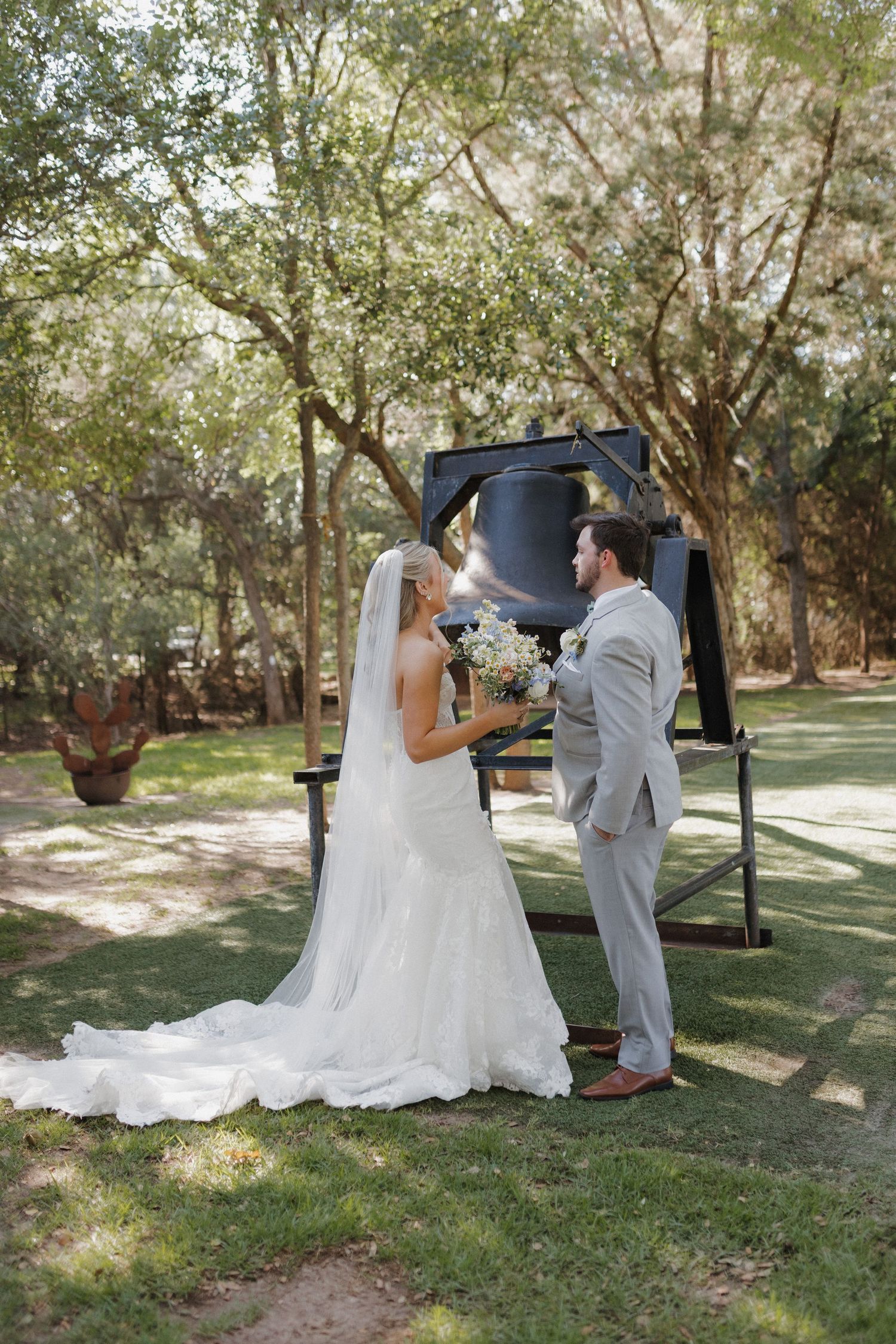 A wedding ceremony moment under trees with white flowers and natural decor.