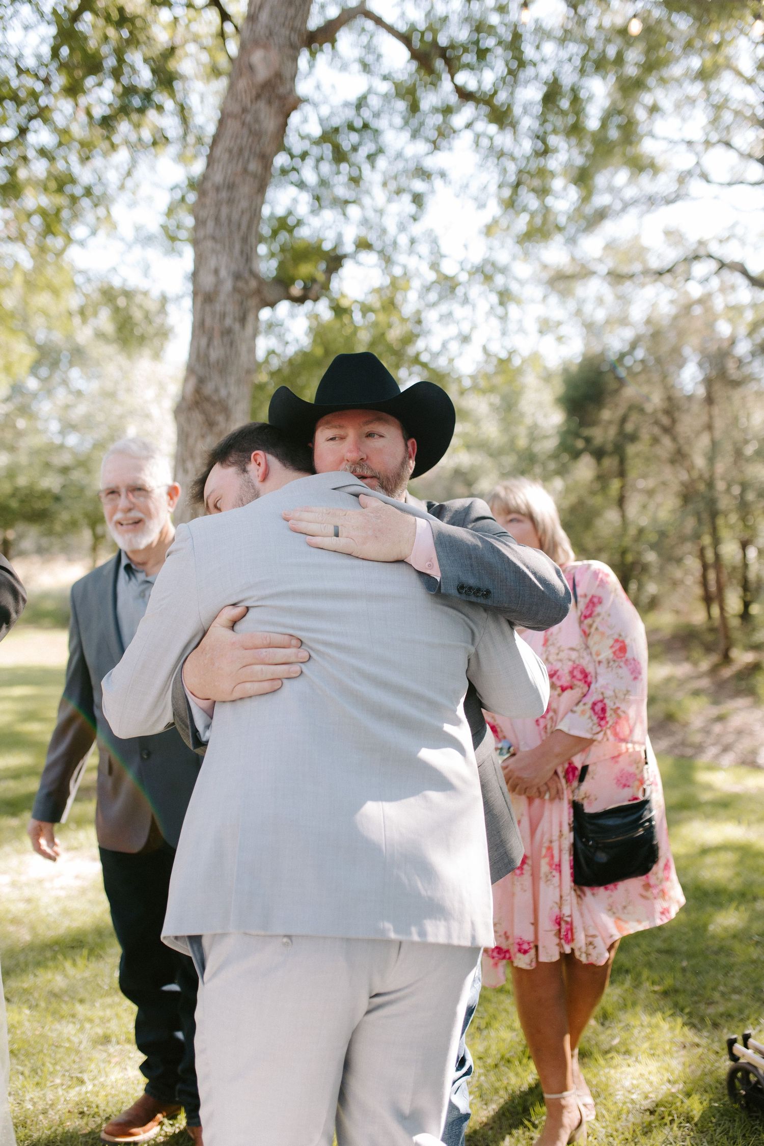 Emotional moment during outdoor wedding as two people share a heartfelt embrace.