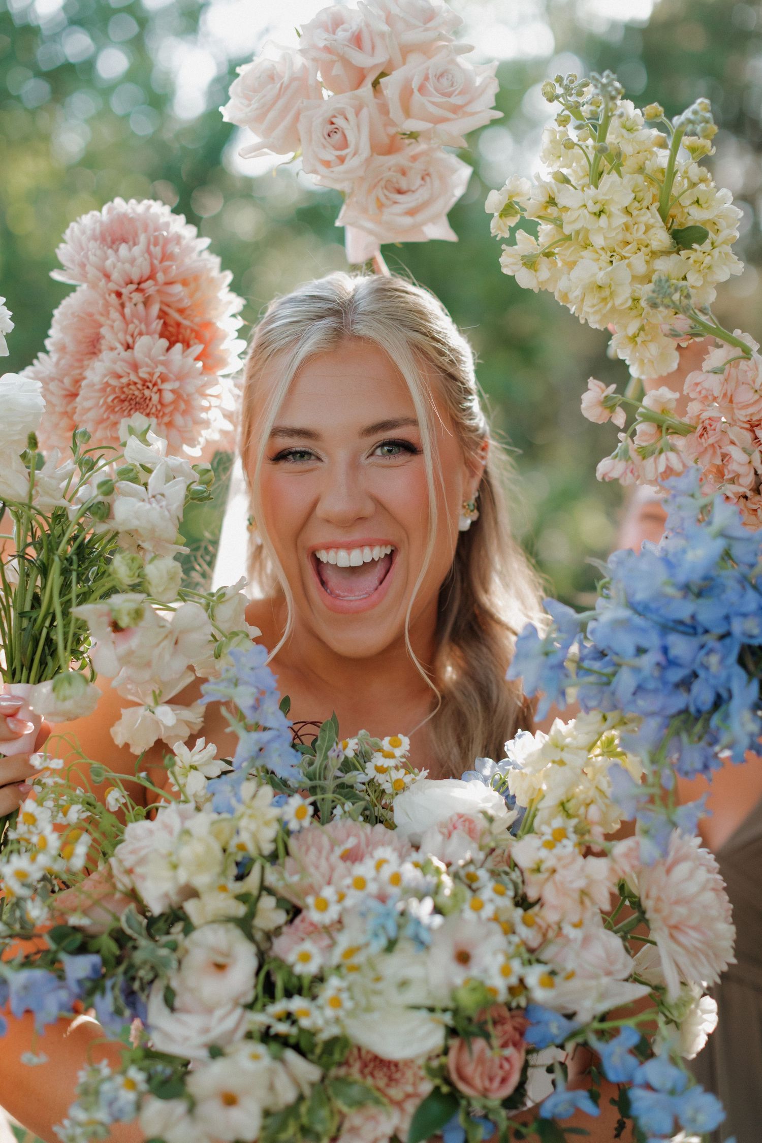 A joyful moment surrounded by pink roses, blue delphiniums, and mixed pastel flowers.