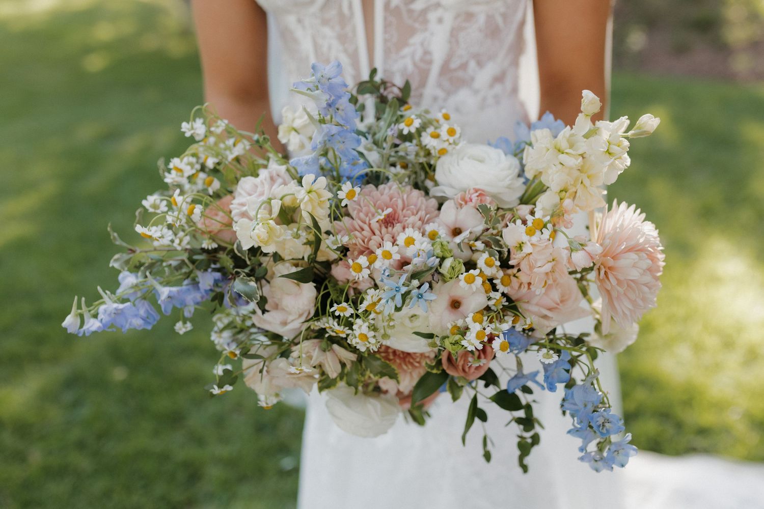 Romantic pastel wedding bouquet features light blue, pink and white flowers with delicate greenery.