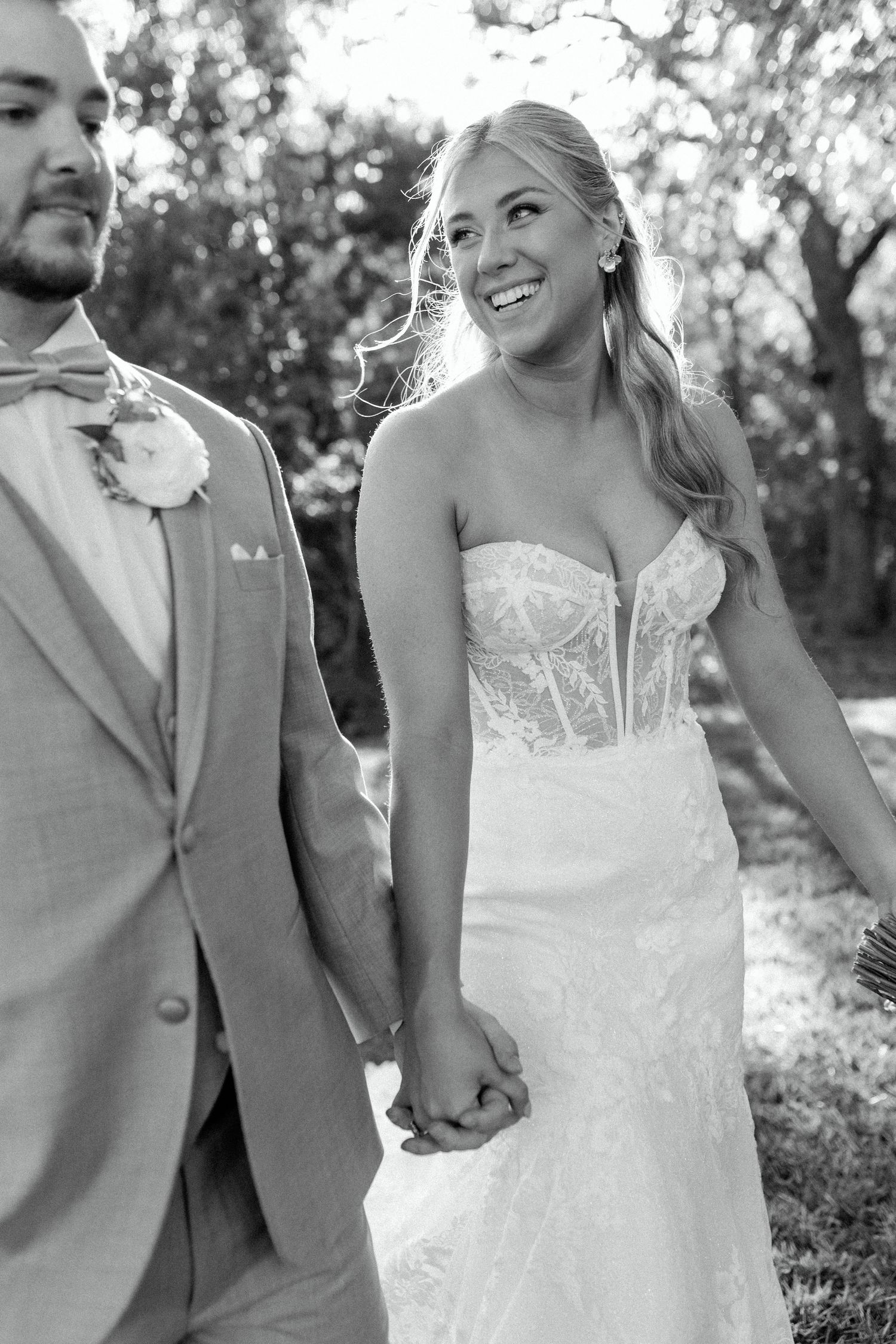 Black and white photo of a couple on their wedding day showing bride in strapless lace gown beside groom.