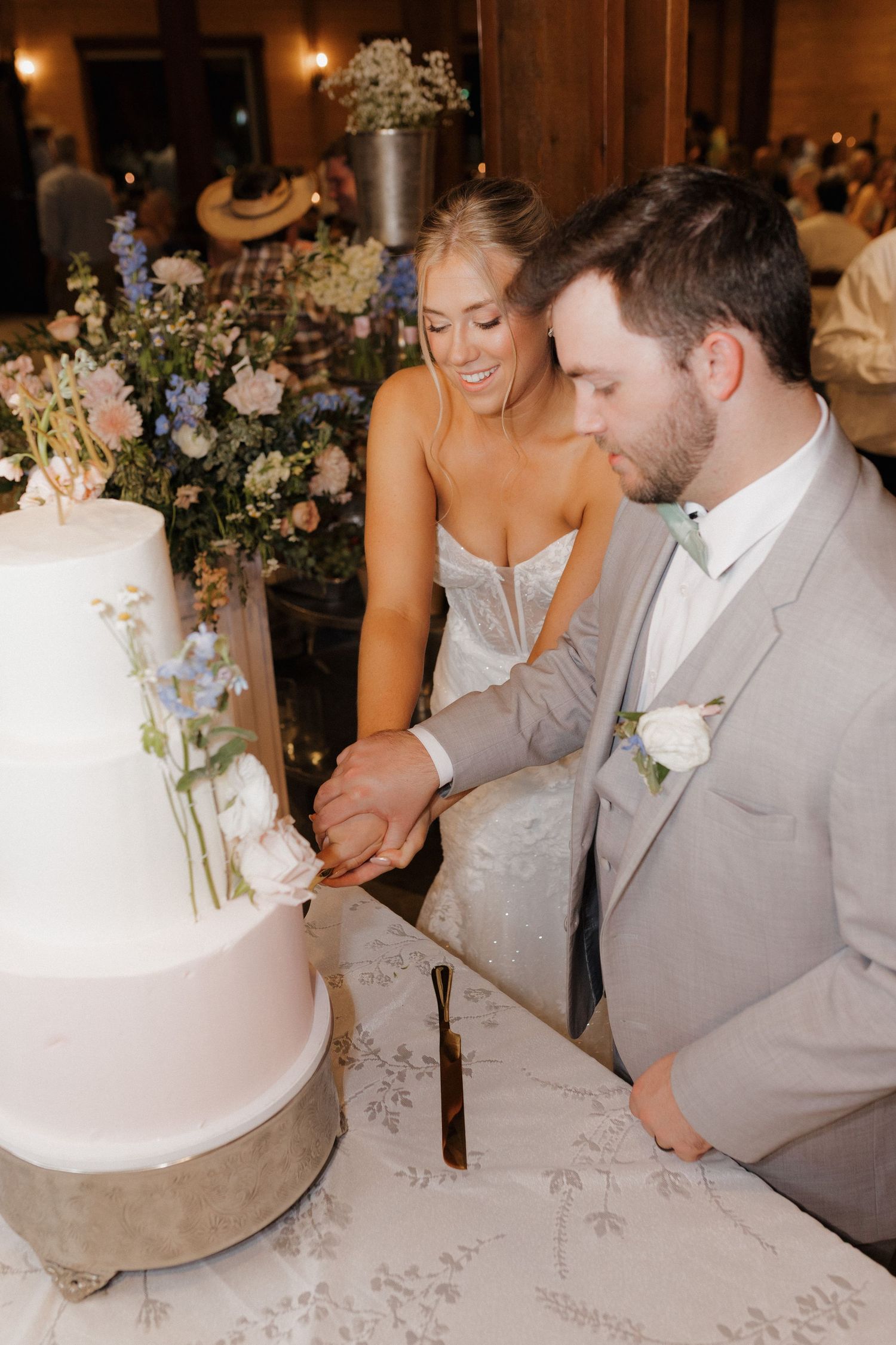 Newlyweds cutting their elegant white wedding cake together at the reception.