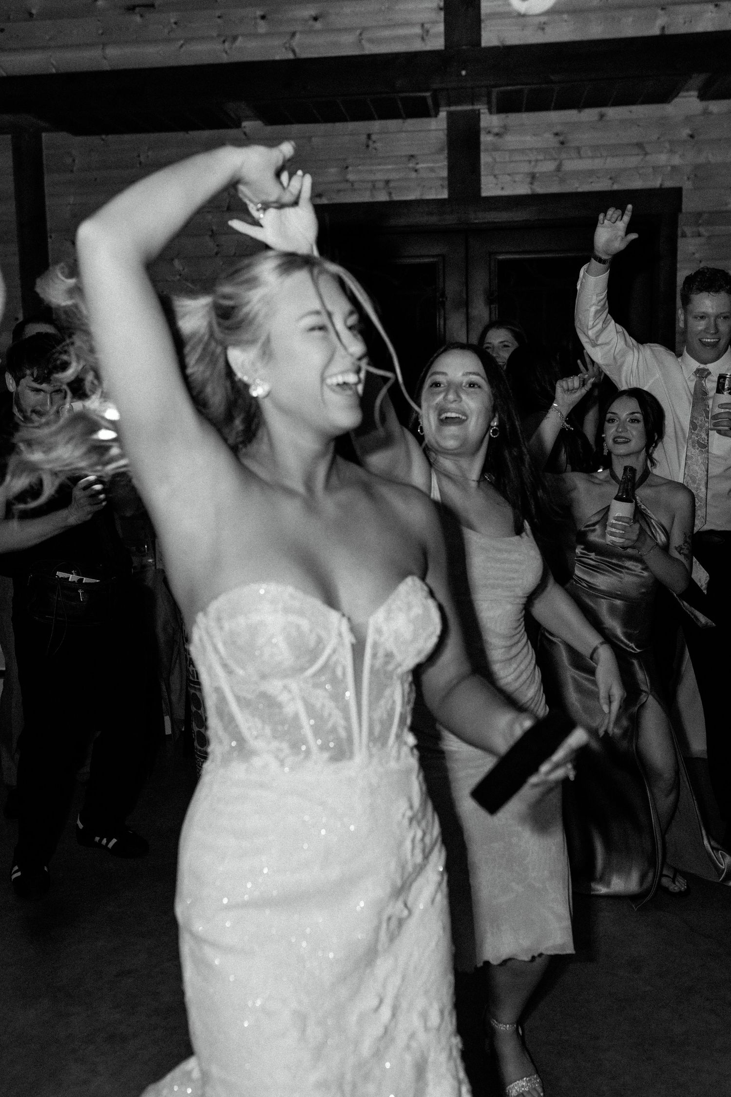 A wedding reception celebration showing joyful dancing with the bride in a white lace strapless gown on the dance floor.