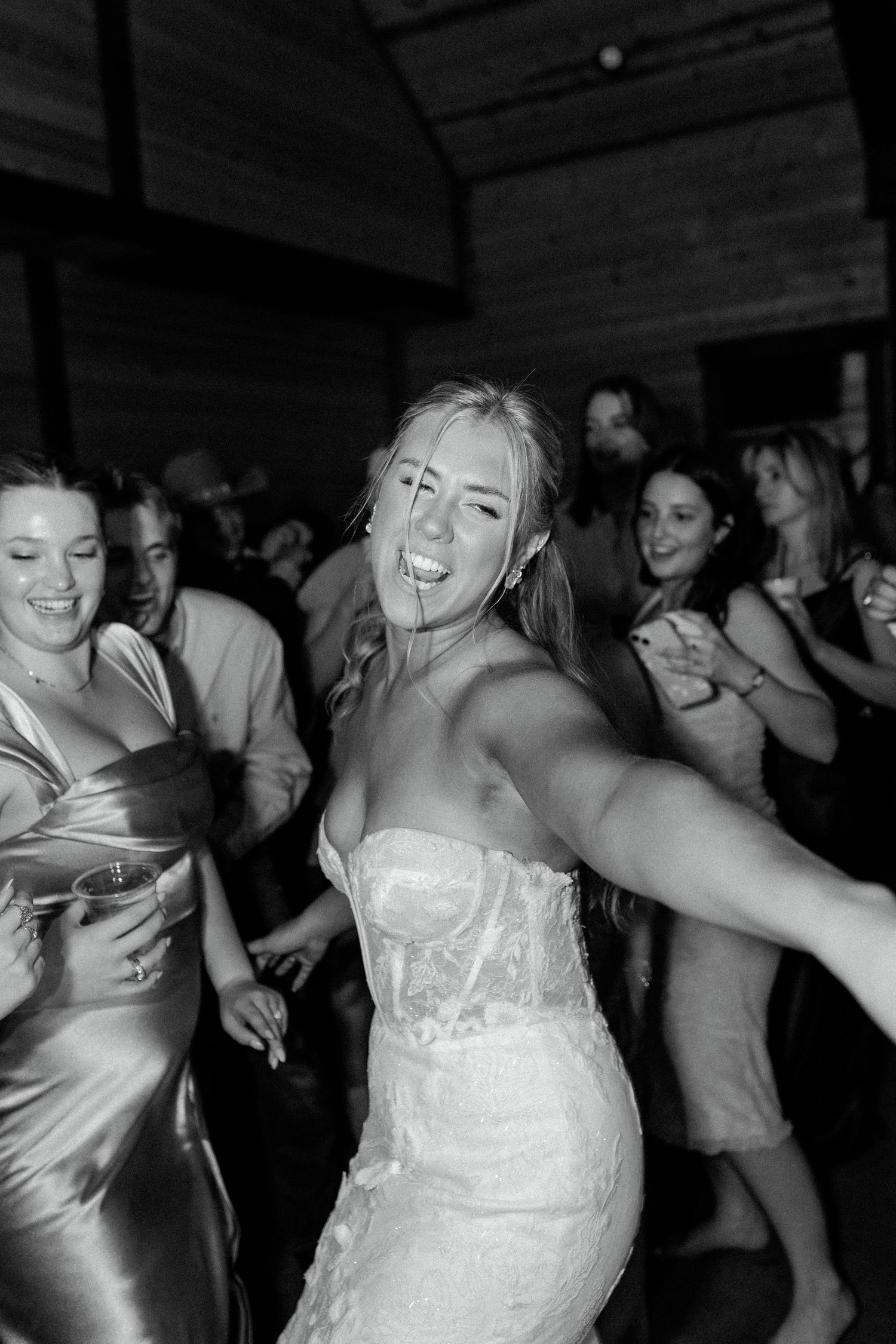 Joyful dancing at a wedding reception as guests celebrate on the dance floor in black and white photography.