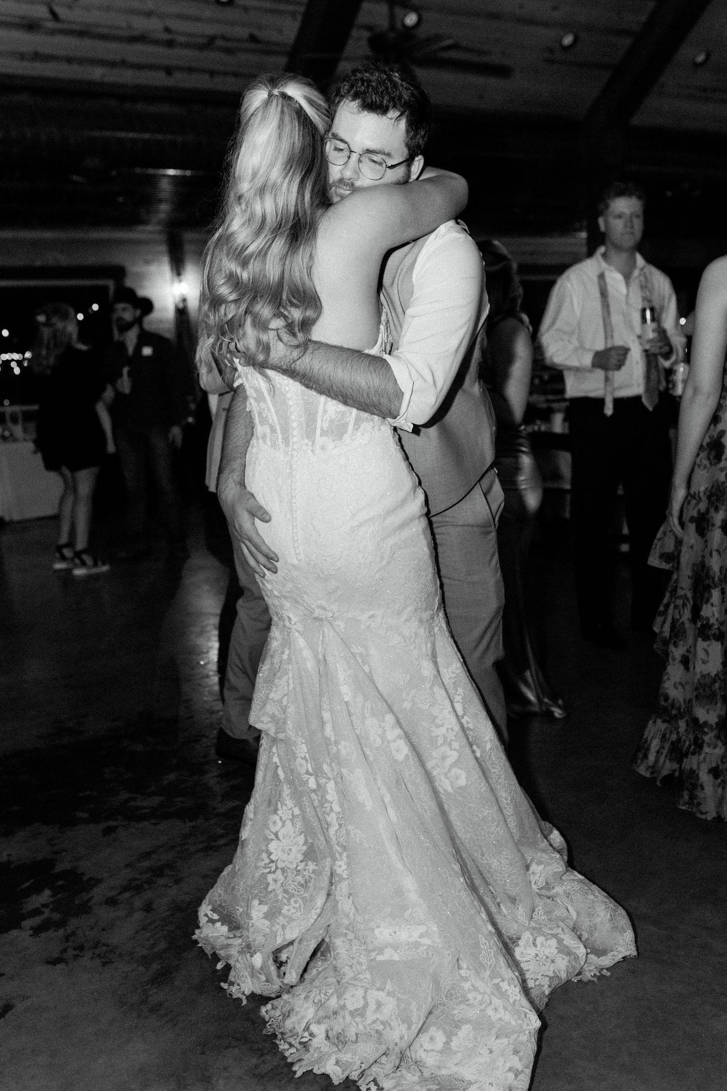 A romantic first dance moment at a wedding reception with the bride wearing a fitted lace gown.
