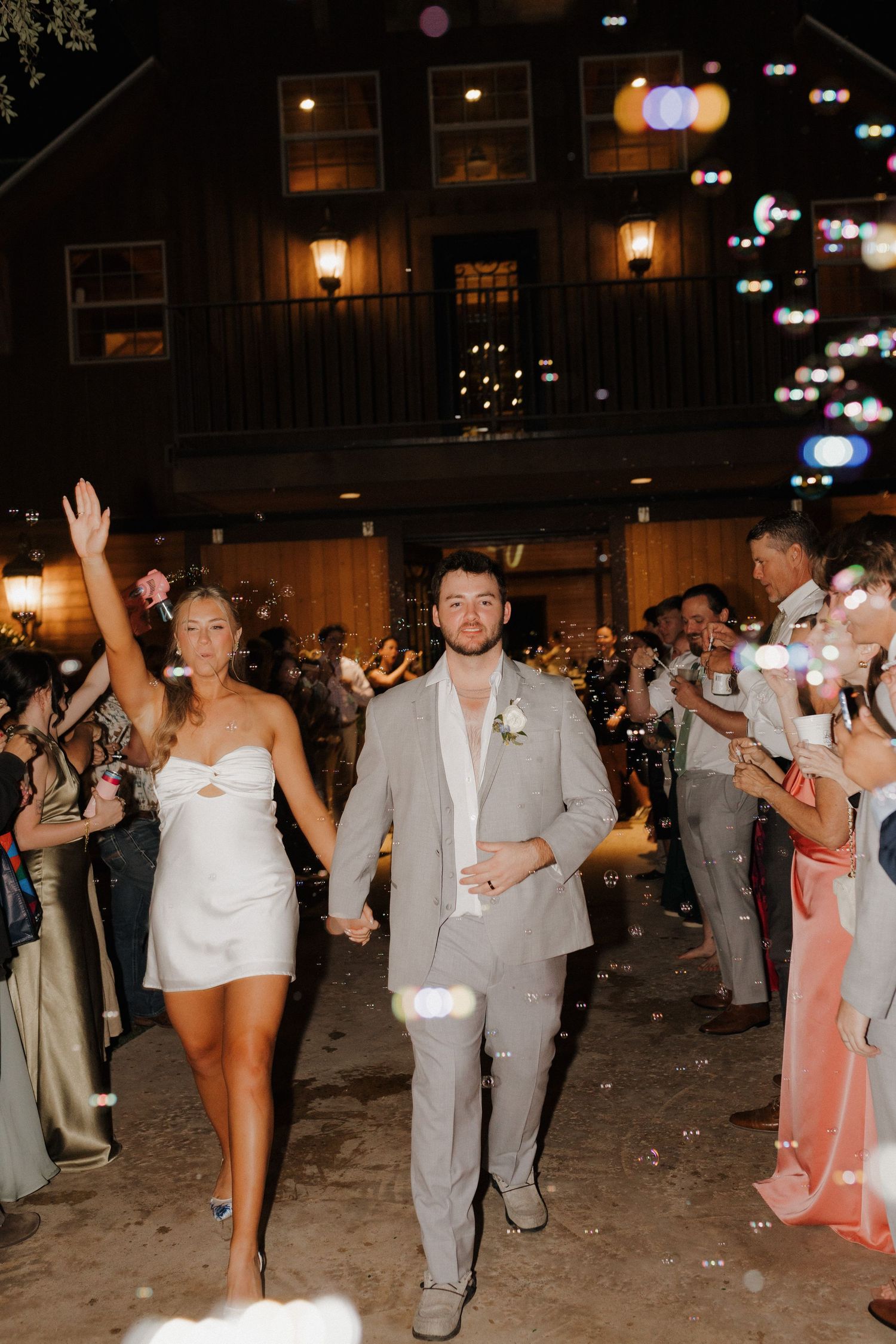 A couple makes their wedding exit through a sparkler-lined pathway at night while guests hold glowing sparklers.
