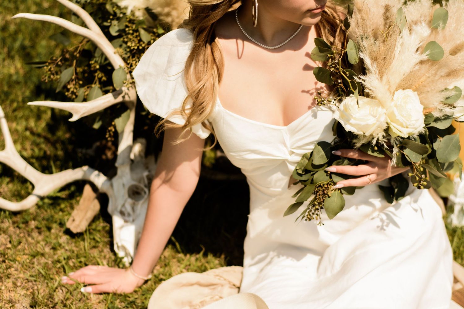 A white wedding bouquet with cascading eucalyptus leaves and delicate blooms is displayed against an elegant backdrop.