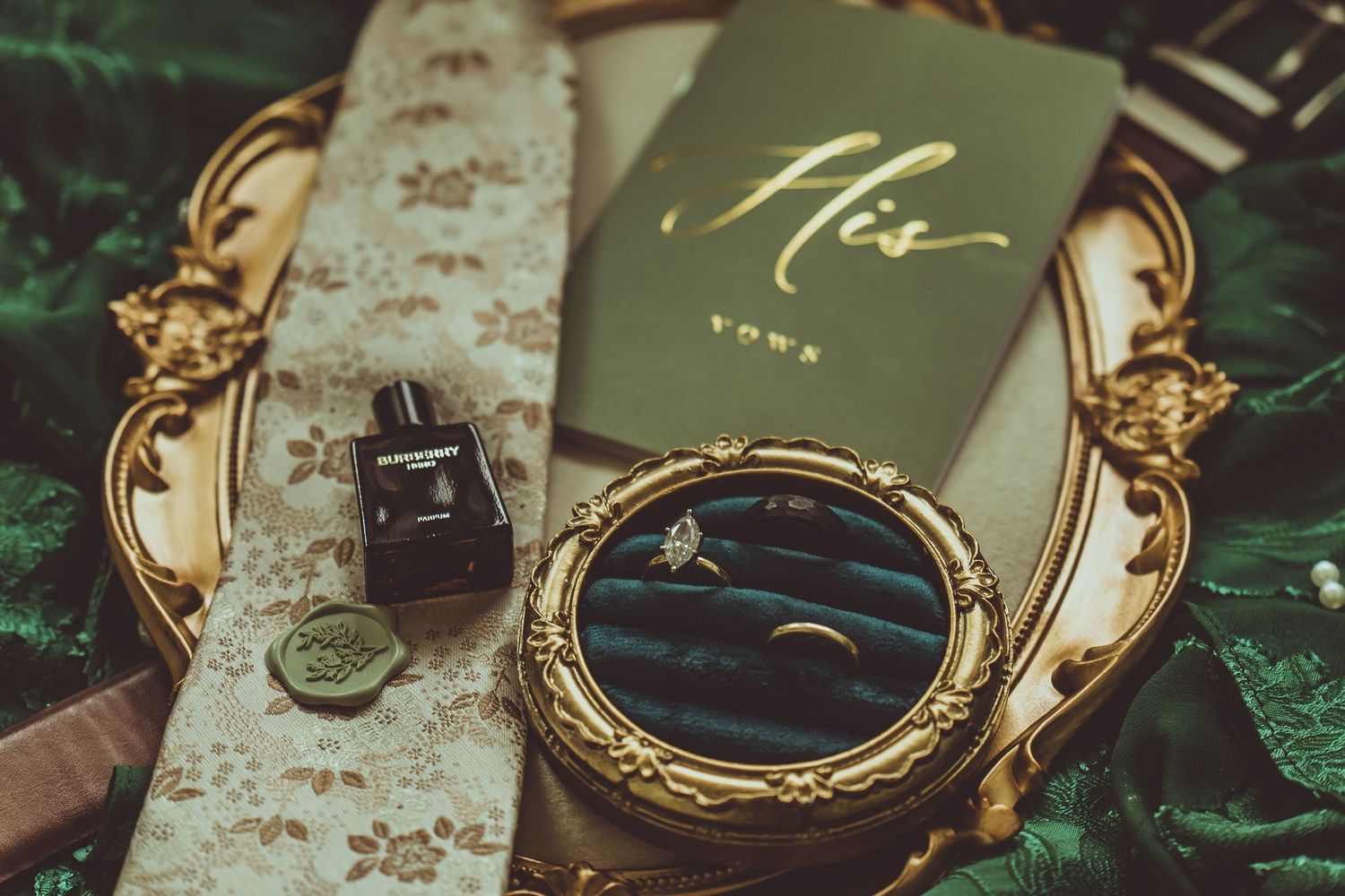 Gold ornate pocket watch with detailed engraving lies open displaying its antique mechanical movement on green velvet fabric.