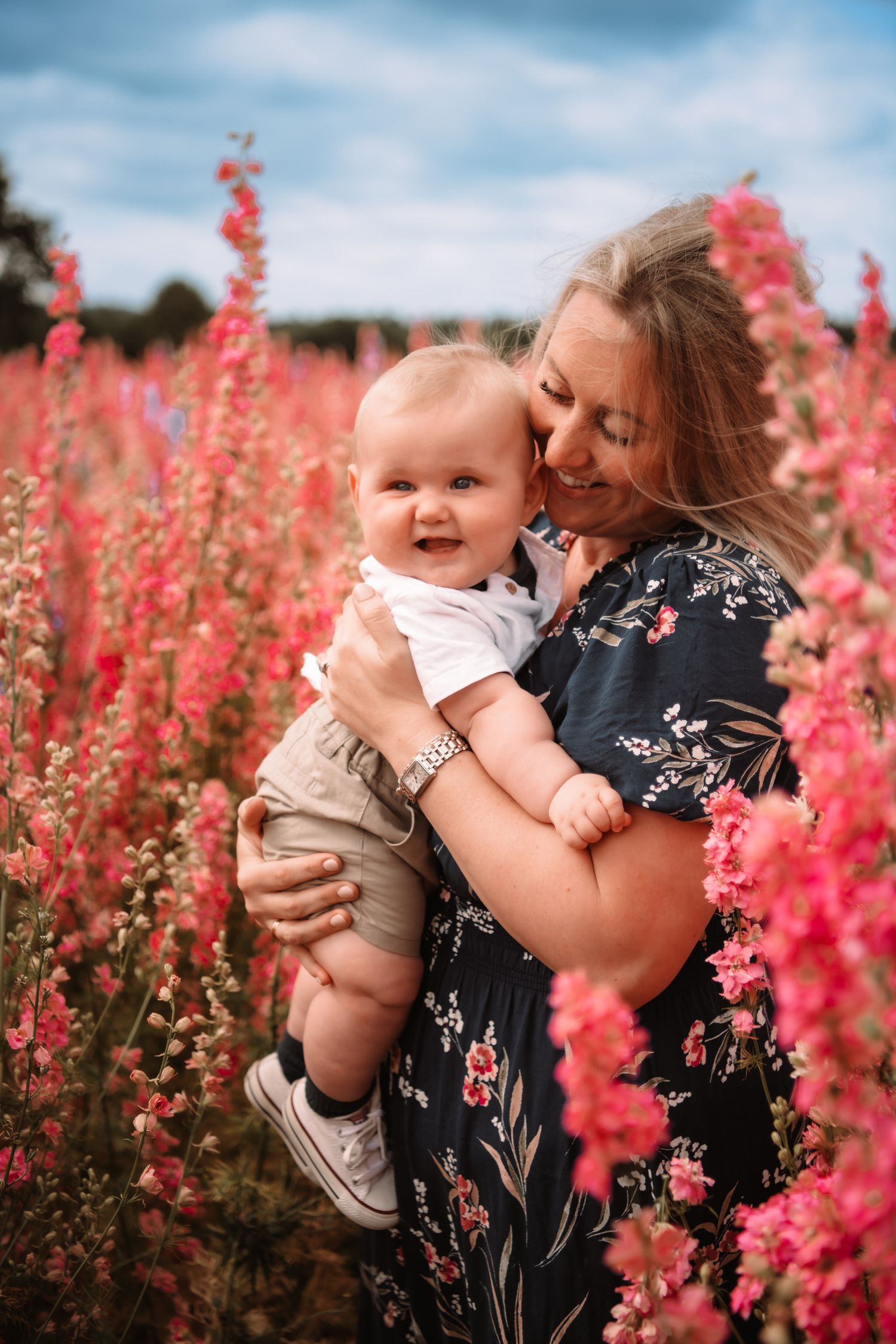A beautiful moment captured in a field of pink snapdragon flowers on a summer day with blue sky overhead.