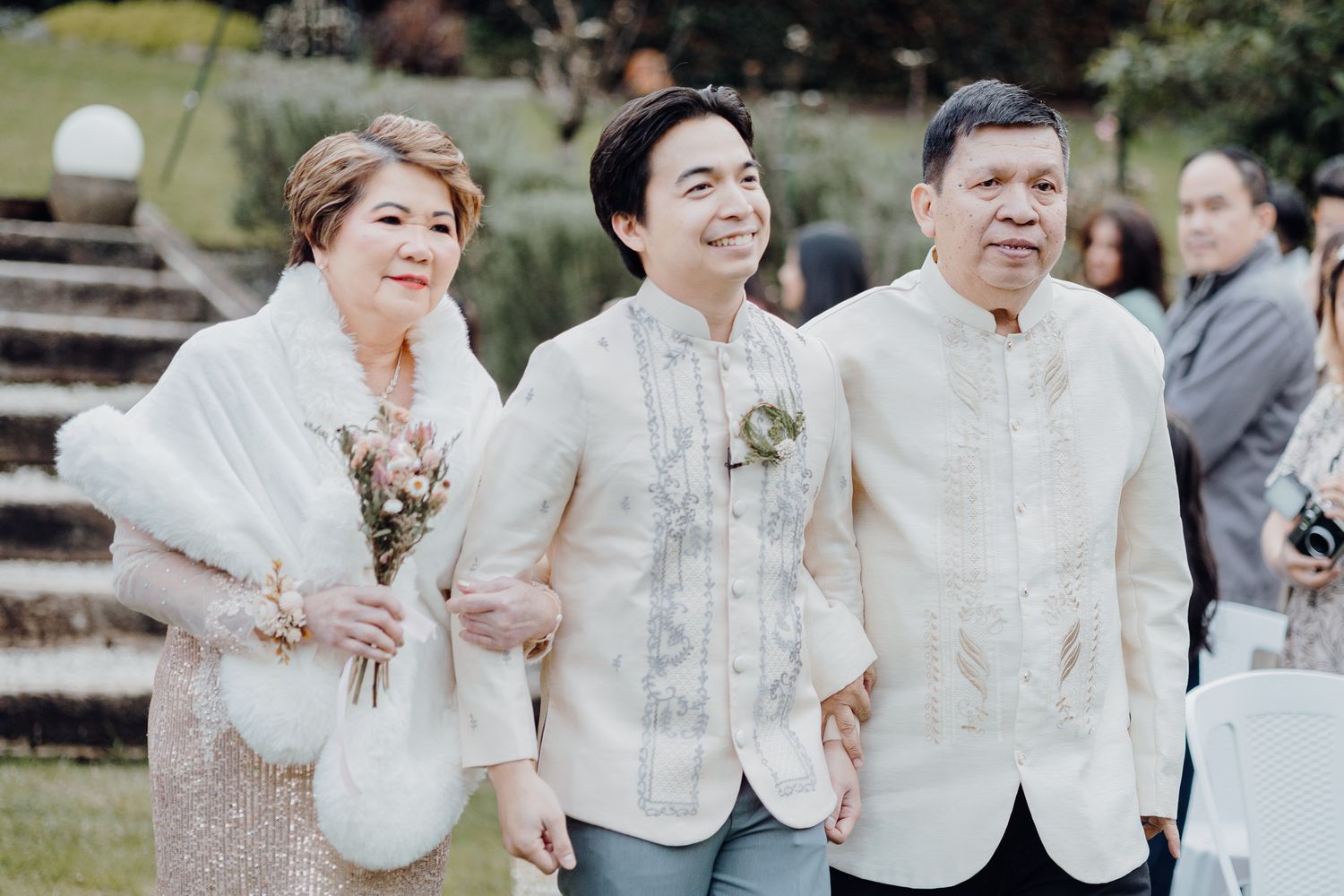 Wedding guests in traditional Filipino formal attire at an outdoor celebration.