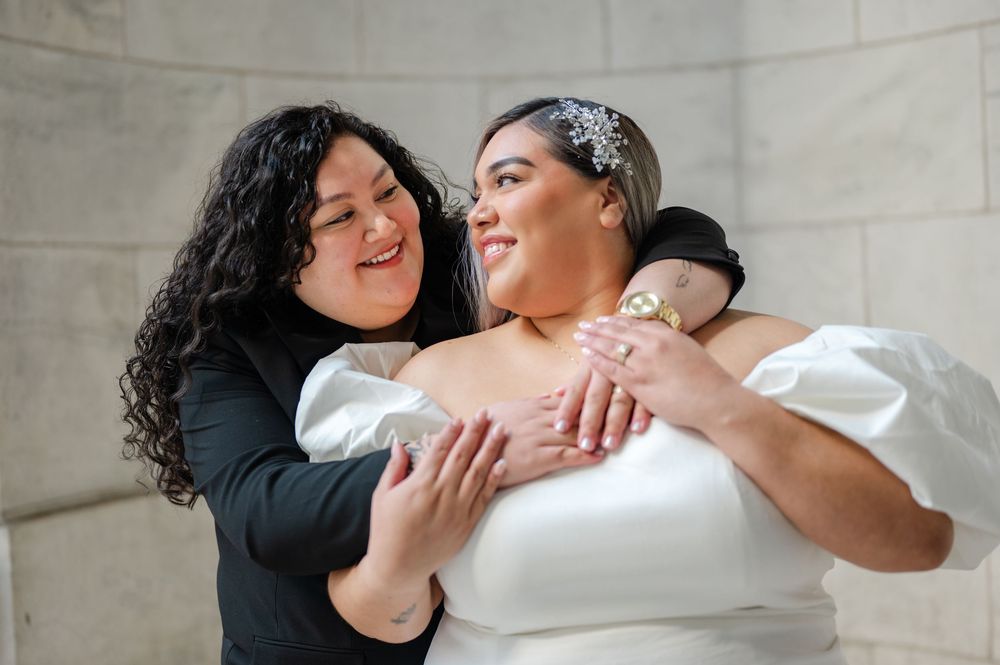 Engaged lesbian couple pose in front of NY Public Library for engagement session