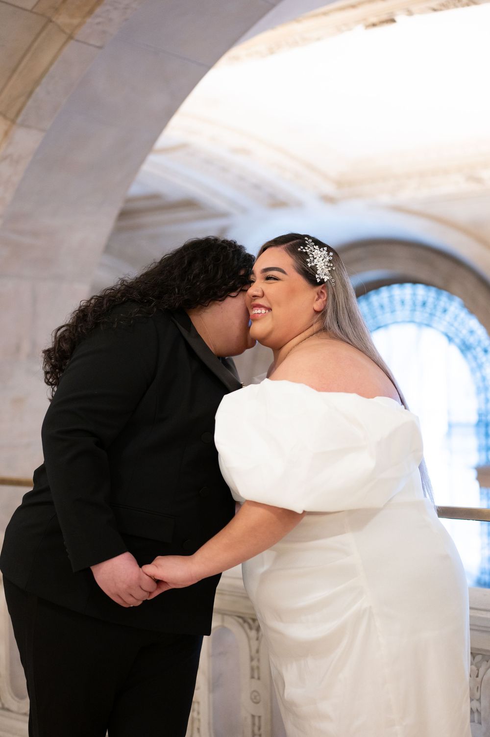 A wedding couple share an intimate moment under an ornate archway in New York Public Library during engagement photos