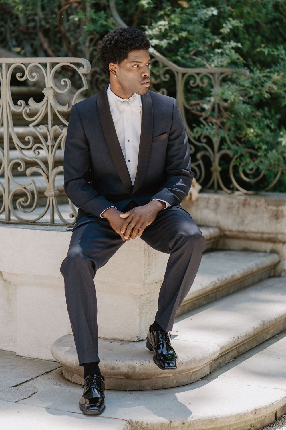 Formal portrait of person in dark suit seated on ornate stone steps.