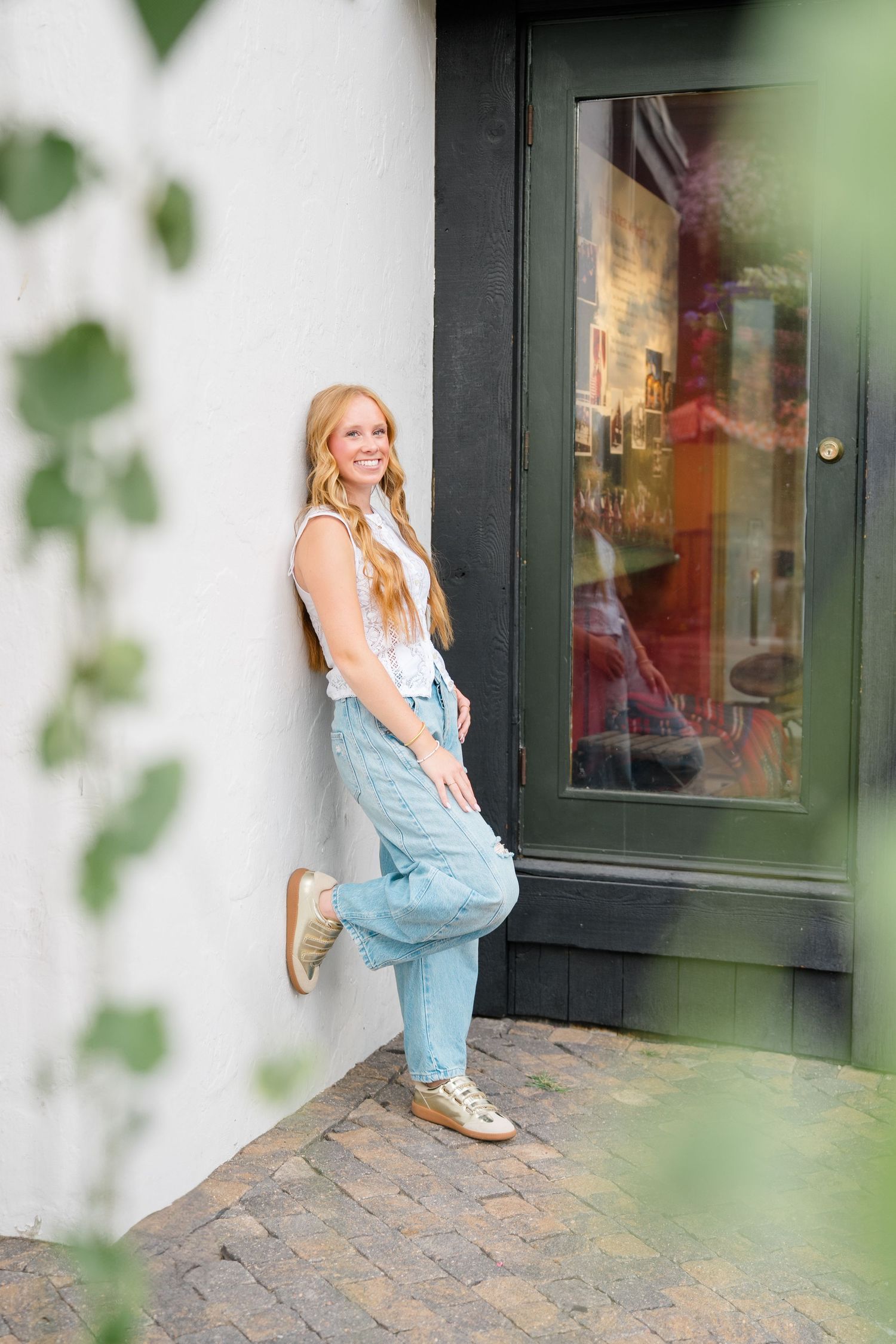 girl against wall in vail village with foot up, ivy hanging