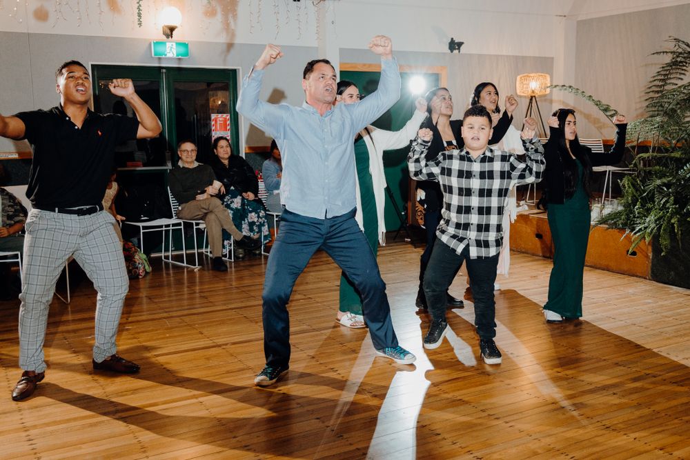 Enthusiastic group dancing in sync on hardwood floors during an indoor event.