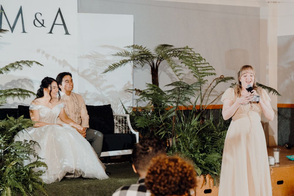 A wedding celebration with speeches and entertainment in a fern-decorated venue.
