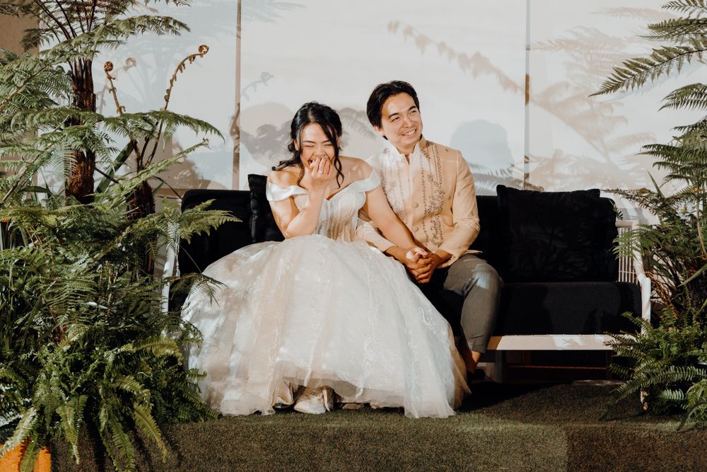 A couple enjoying a moment during their wedding reception in front of a piano and fern decor.