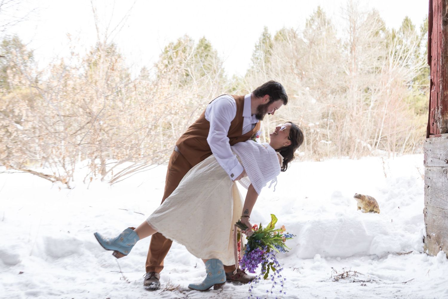 A romantic winter scene shows a couple dancing in the snow with a bouquet of flowers nearby.