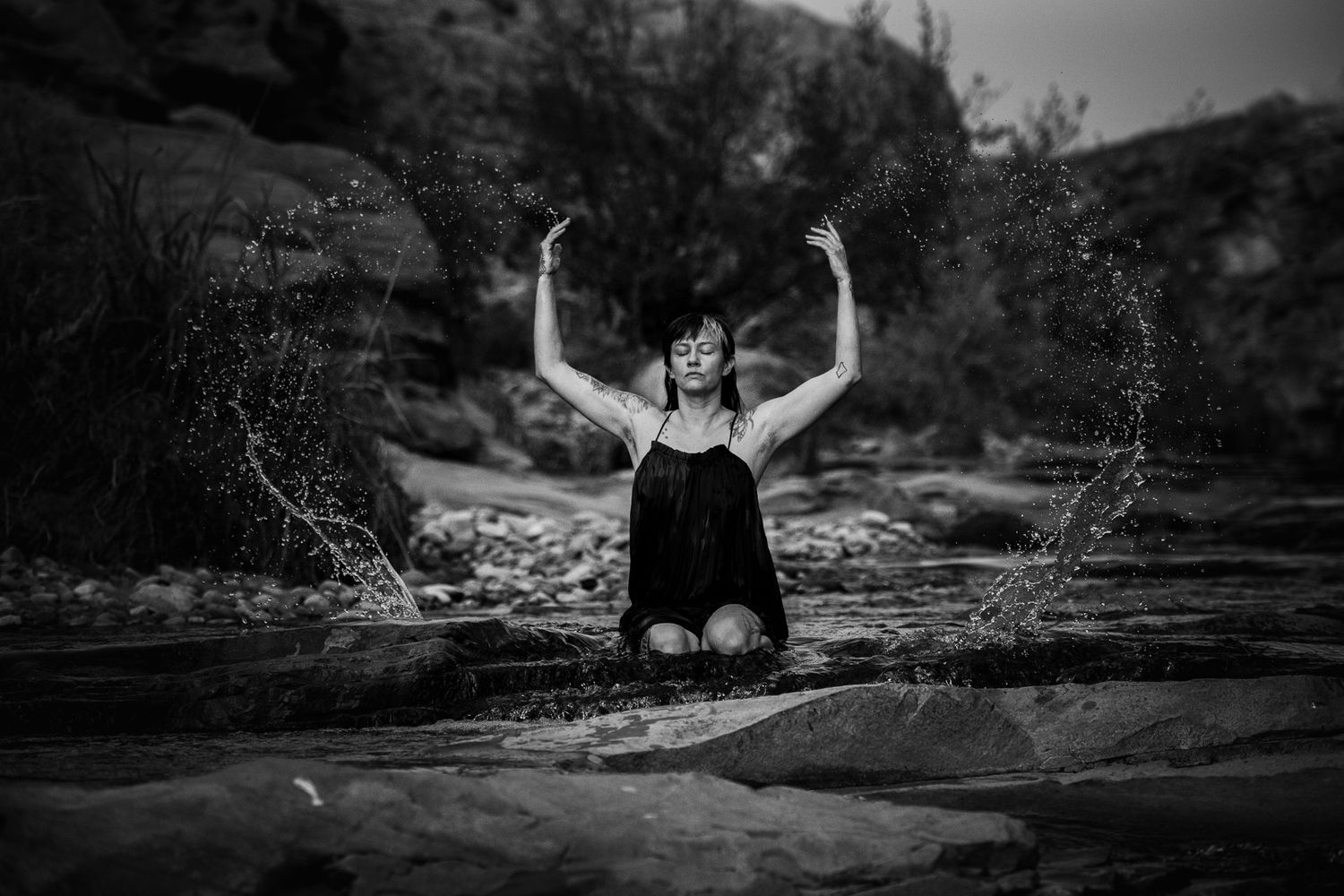Silhouette of someone splashing water in a dramatic black and white nature scene.