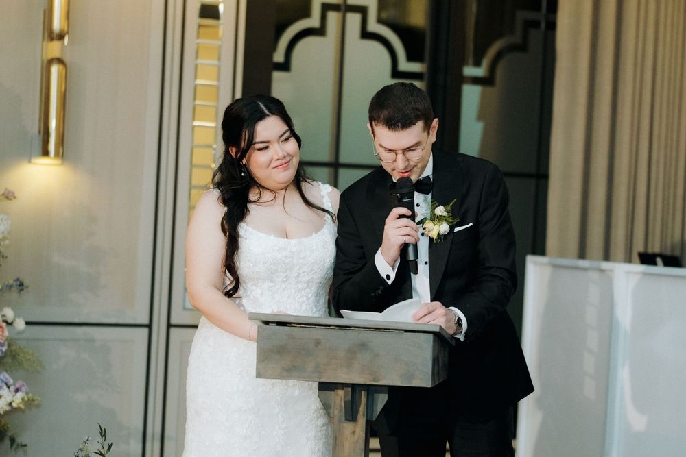 Couple cutting their wedding cake together at elegant venue with art deco details.