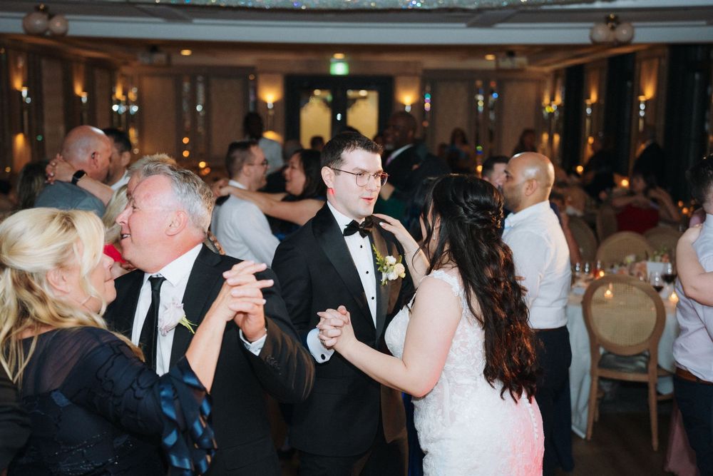 Wedding guests enjoying dancing and celebration in a beautifully lit ballroom venue.
