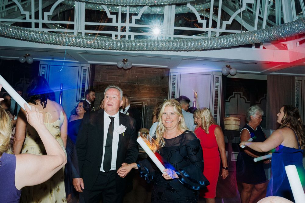 Energetic wedding reception with guests dancing under colorful party lights.