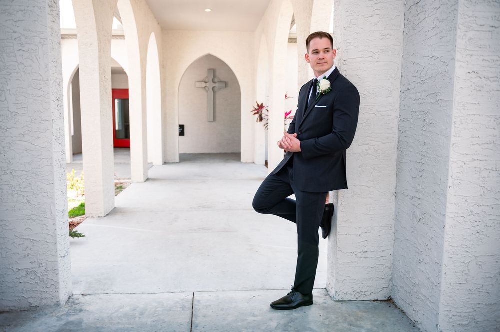 Groom leaning against wall in classic black tux at Canterbury Hall, Tampa wedding day portrait