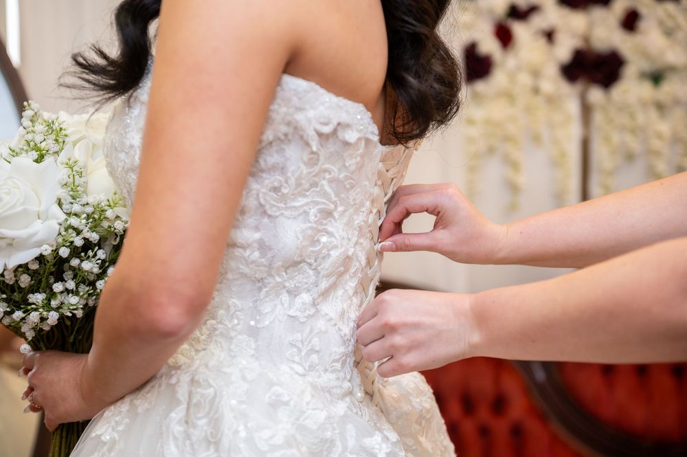 A bridesmaid ties the back of the bride's dress during the wedding day at Canterbury Hall in Tampa.