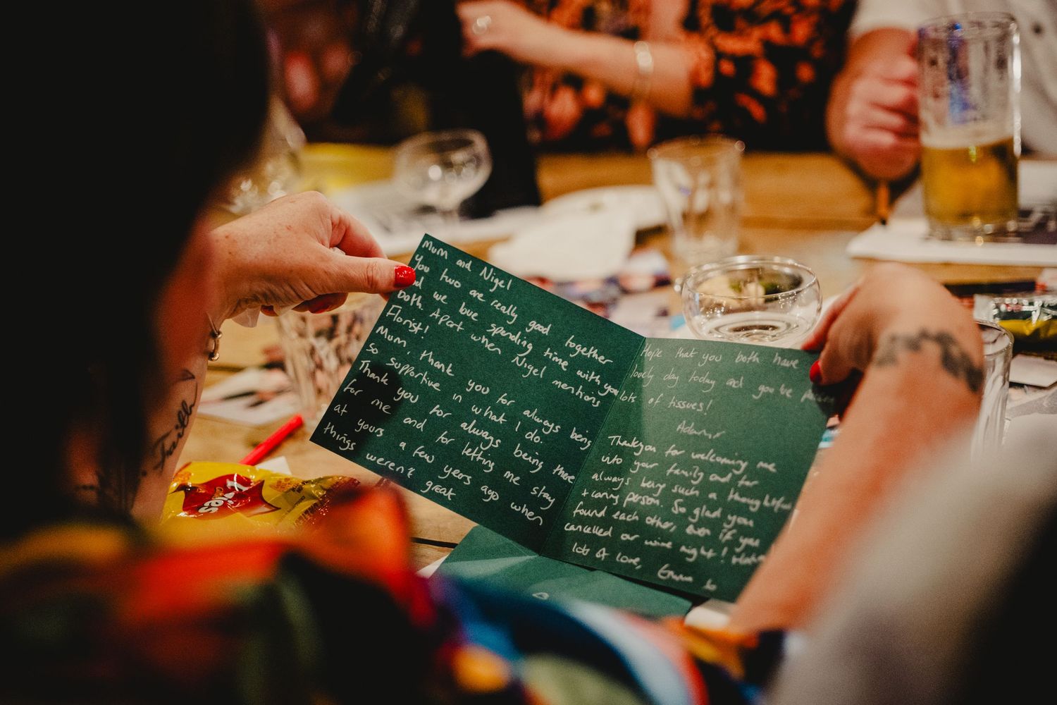 Someone holds a green chalkboard menu at a restaurant table while dining with glasses and dishes visible.