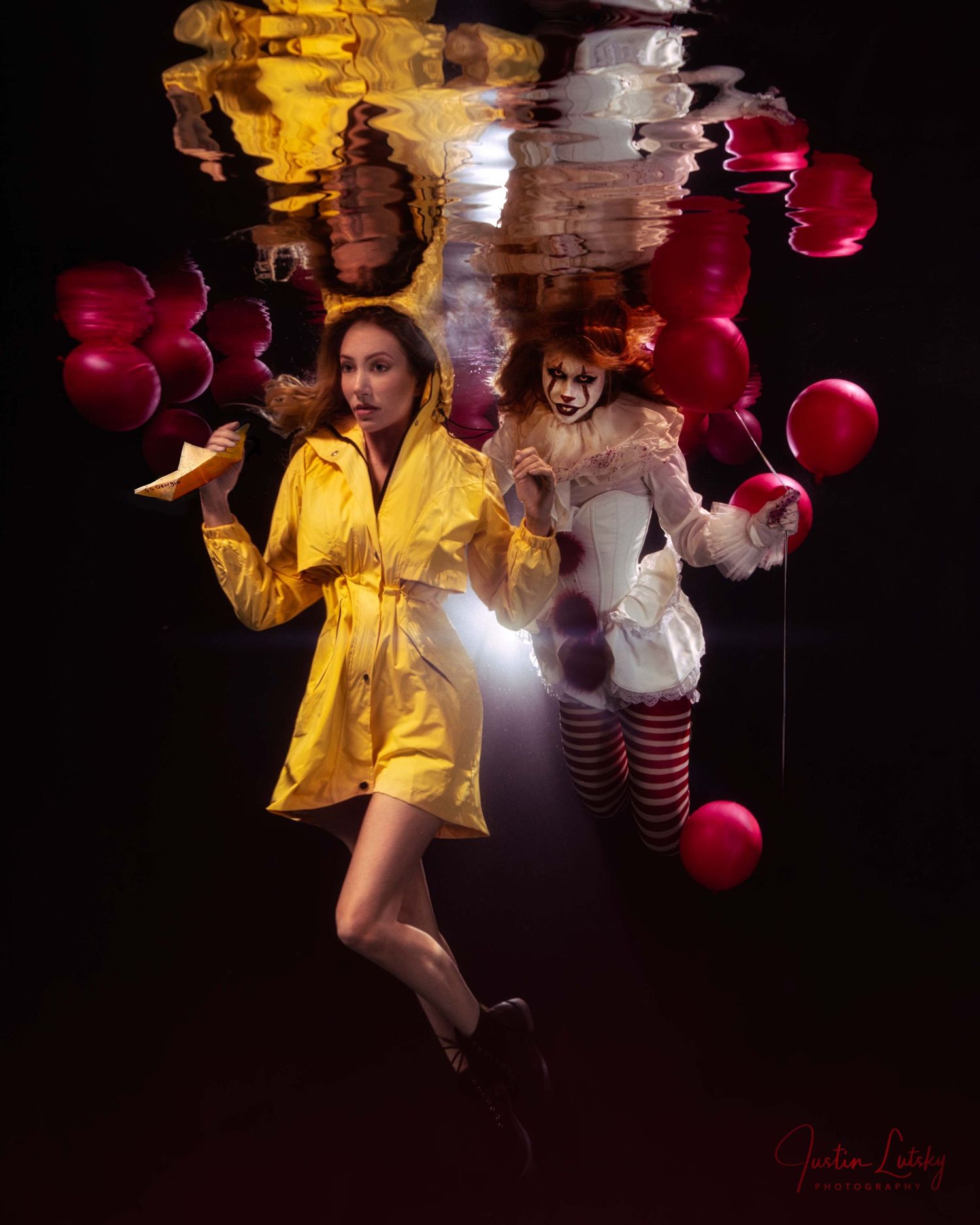 Dark artistic portrait with yellow raincoat and striped performer surrounded by red balloons and light effects.