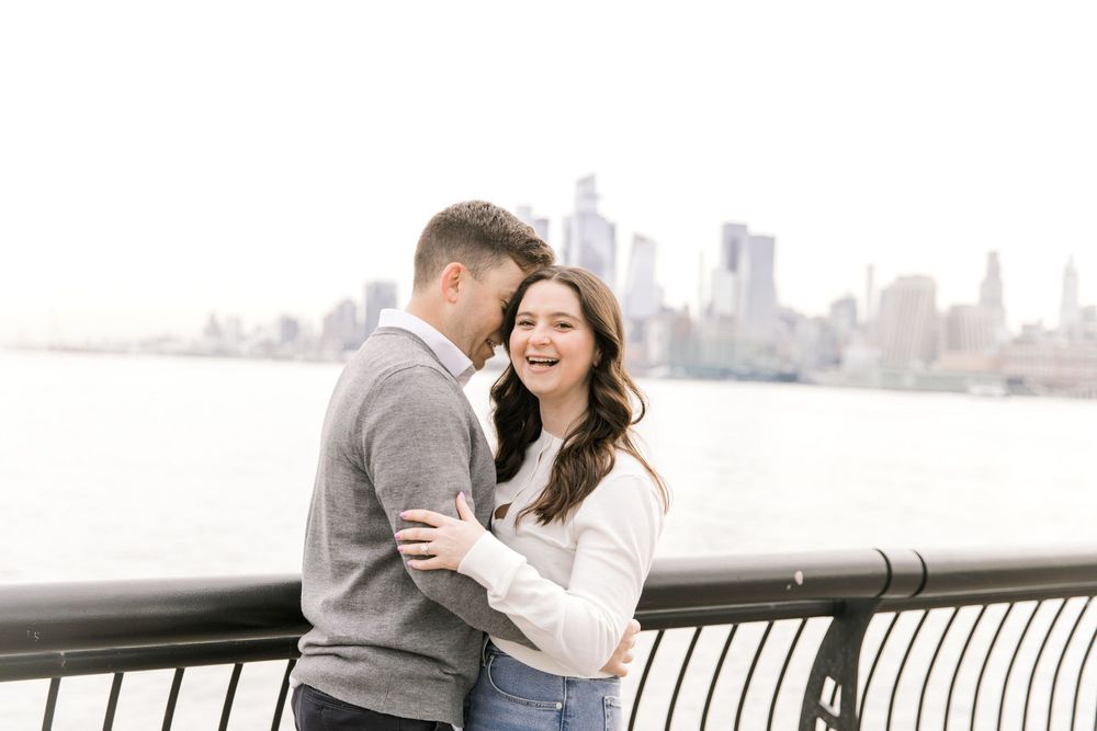 Engaged couple sharing a romantic moment with Manhattan skyline views at Pier A Park.