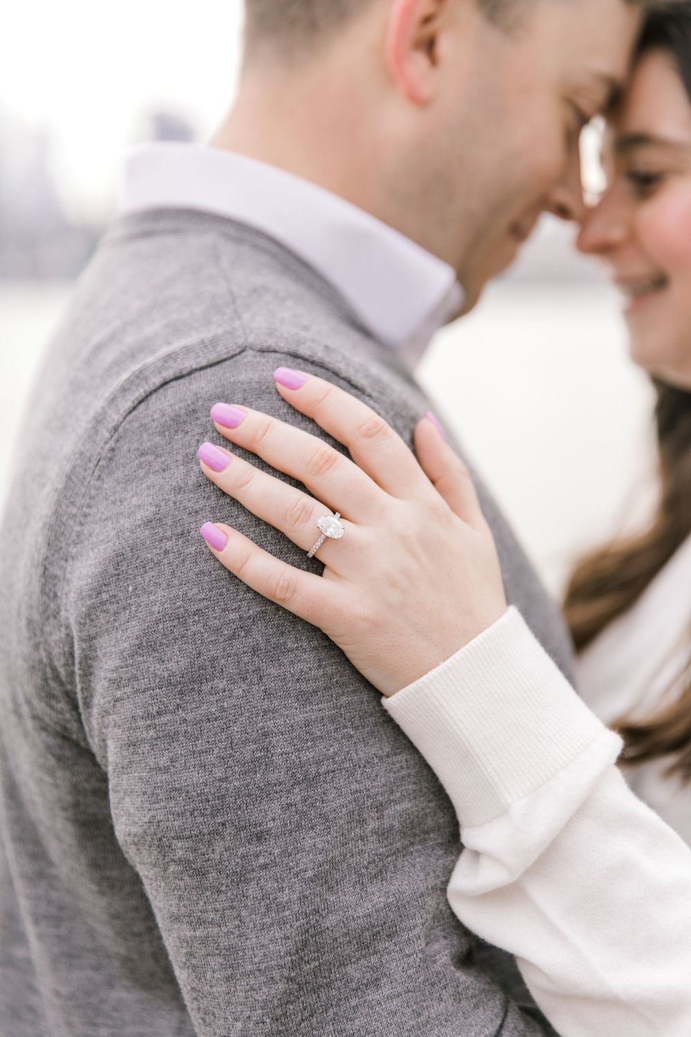 Engaged couple sharing a romantic moment with Manhattan skyline views at Pier A Park.