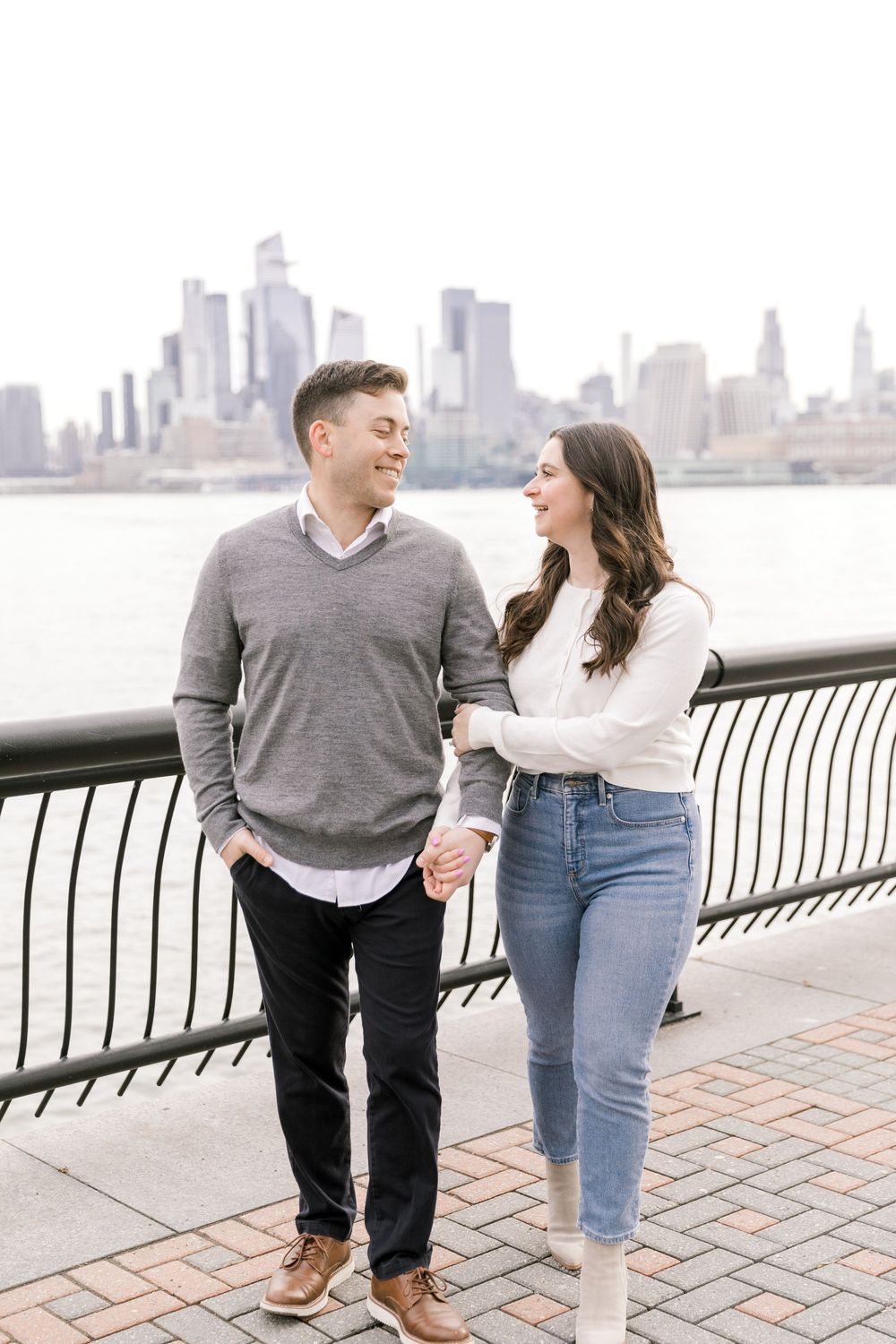 Engaged couple sharing a romantic moment with Manhattan skyline views at Pier A Park.