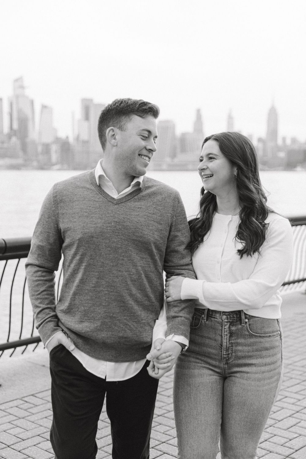 Engaged couple sharing a romantic moment with Manhattan skyline views at Pier A Park.
