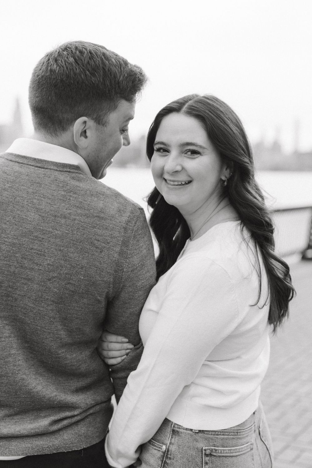 Engaged couple sharing a romantic moment with Manhattan skyline views at Pier A Park.
