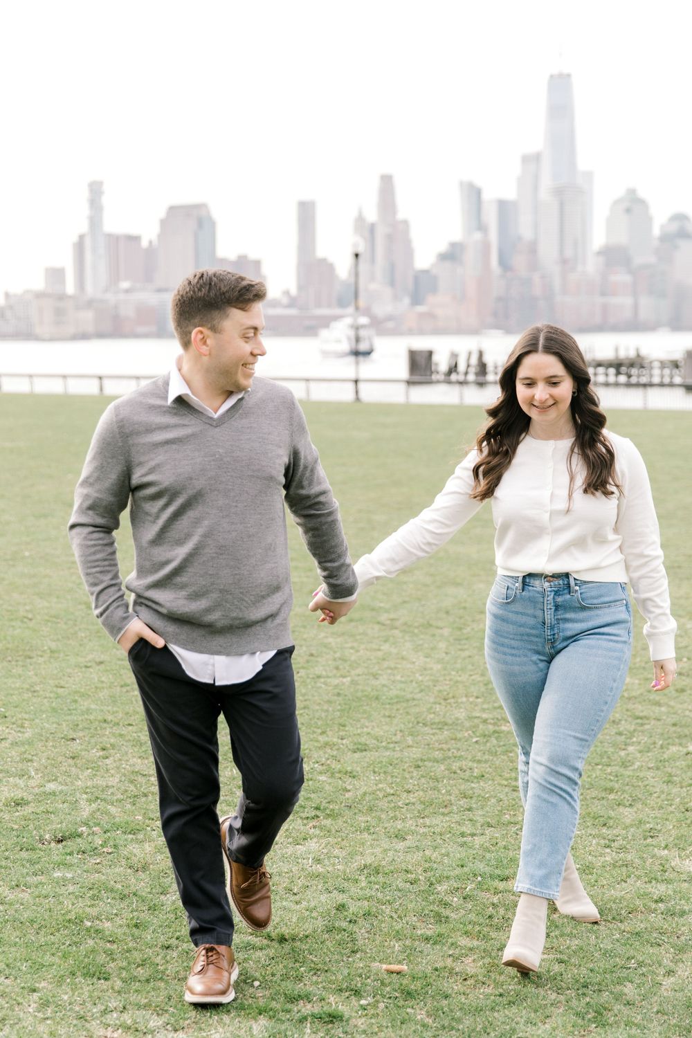 Engaged couple sharing a romantic moment with Manhattan skyline views at Pier A Park.