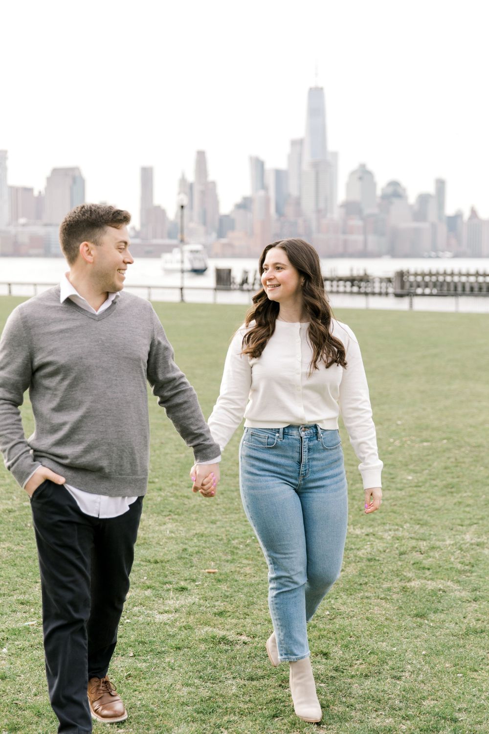 Engaged couple sharing a romantic moment with Manhattan skyline views at Pier A Park.