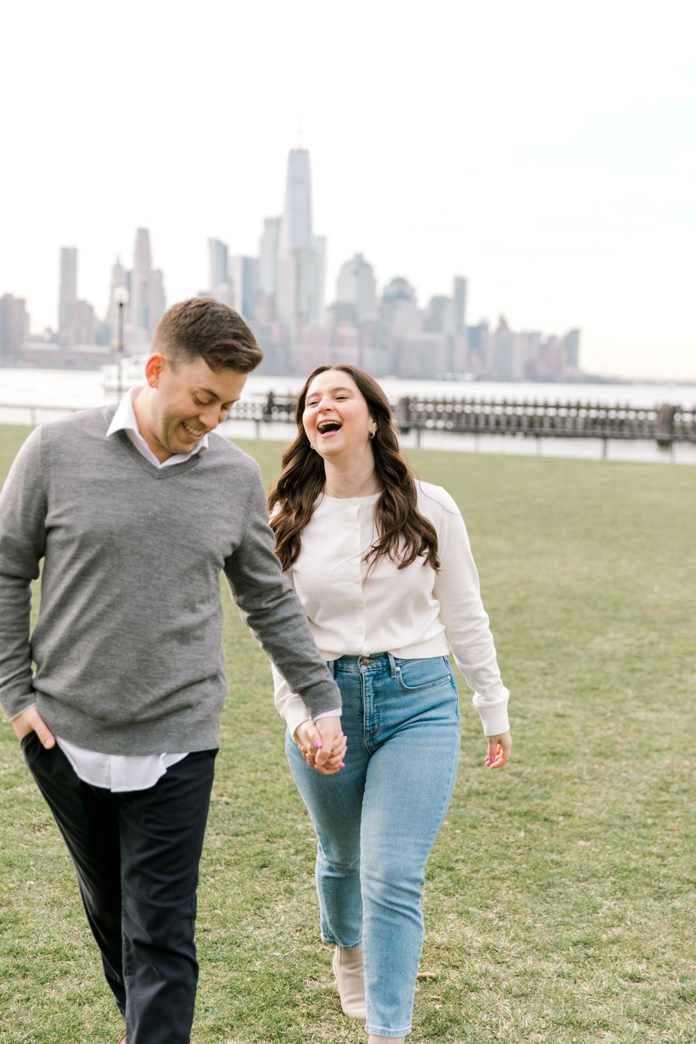 Engaged couple sharing a romantic moment with Manhattan skyline views at Pier A Park.