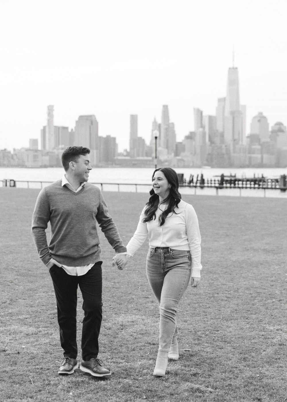 Engaged couple sharing a romantic moment with Manhattan skyline views at Pier A Park.