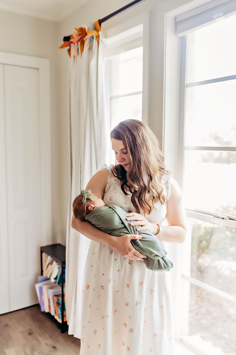 A tender moment between parent and child near bright sunlit windows in a cozy white room.