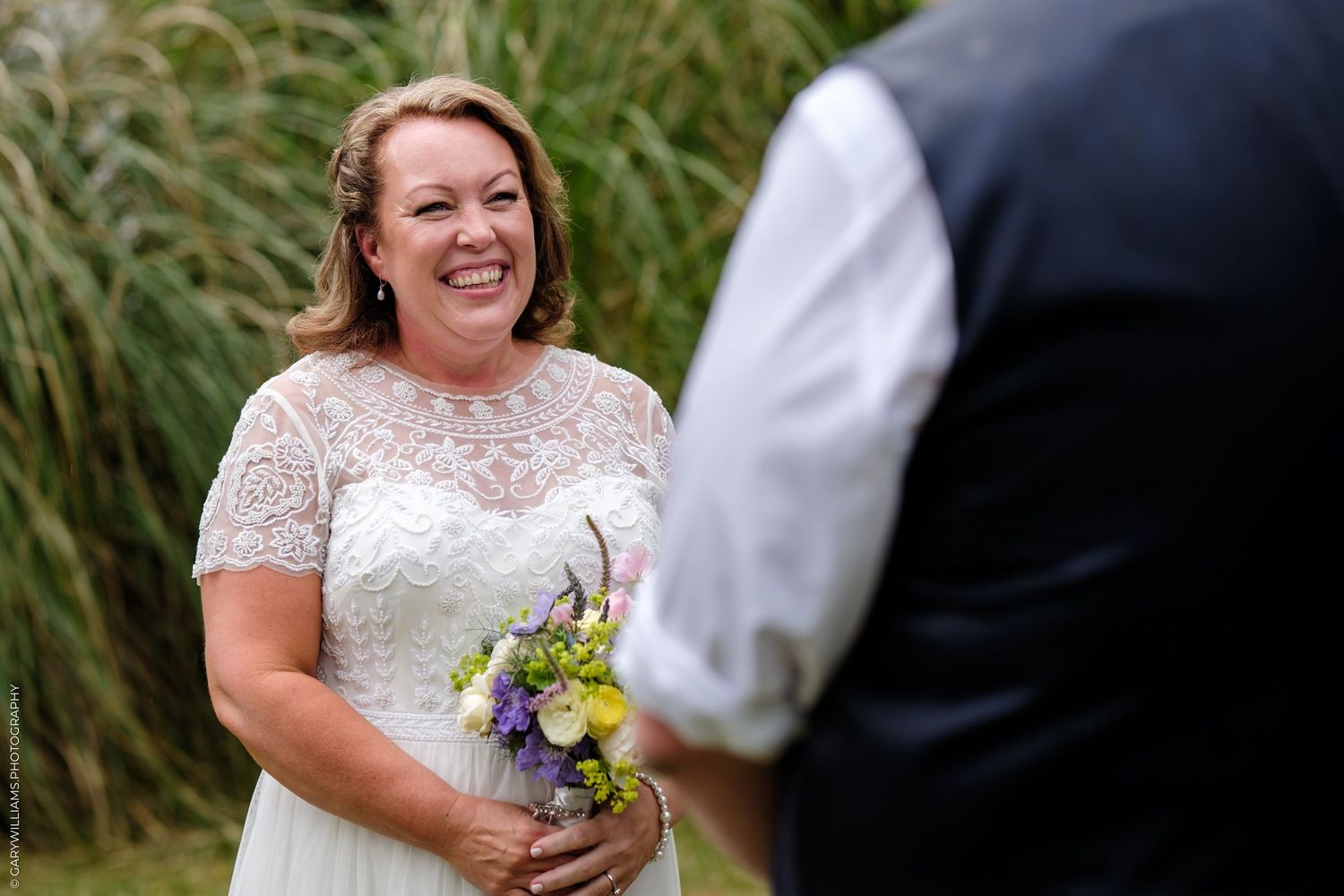 Four wedding photos show candid moments between a bride in a white lace dress and groom during an outdoor ceremony.