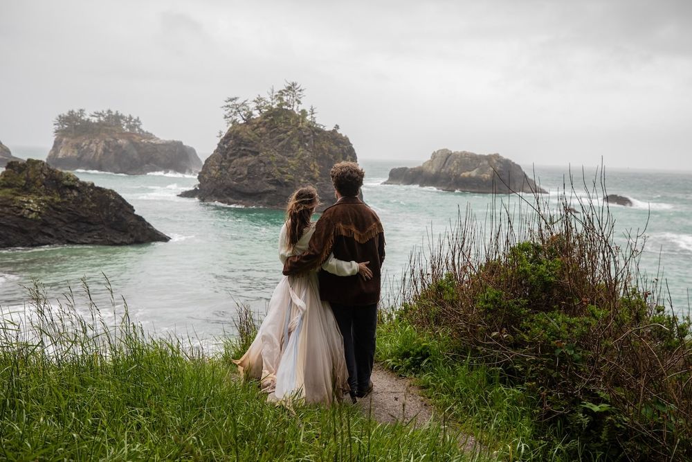 couple standing by a waterfall in wedding attire on Oregon coast