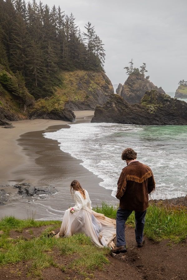 couple standing by a waterfall in wedding attire on Oregon coast