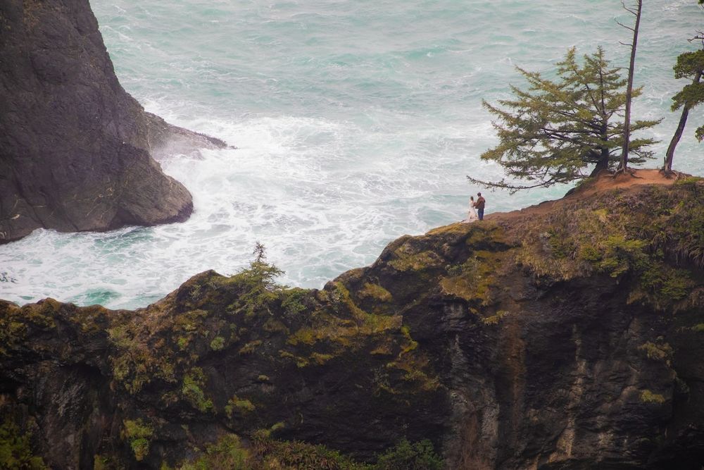 couple standing by a waterfall in wedding attire on Oregon coast