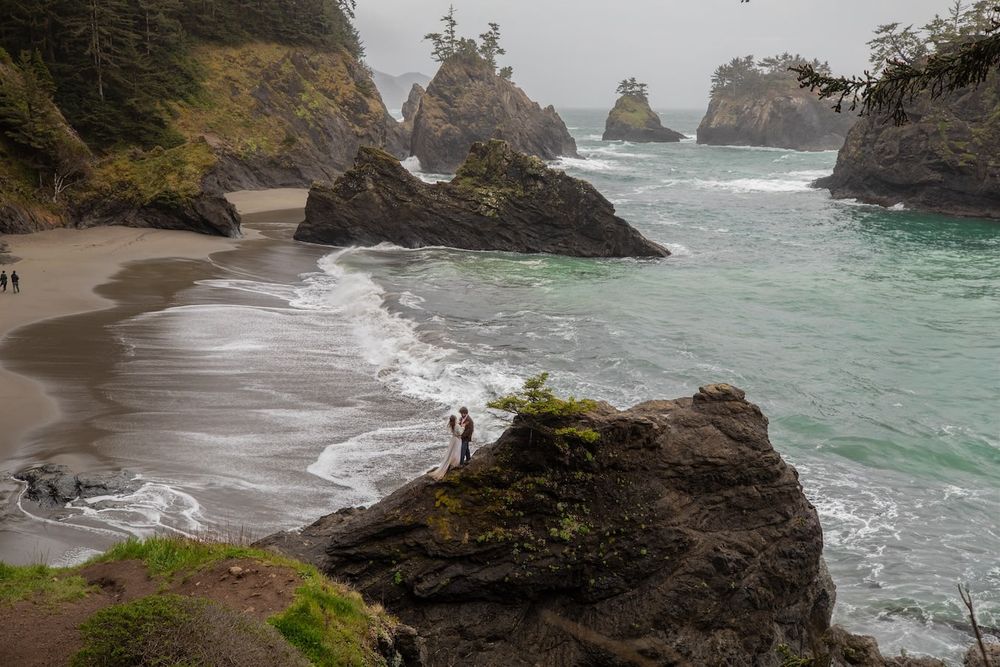 couple standing by a waterfall in wedding attire on Oregon coast