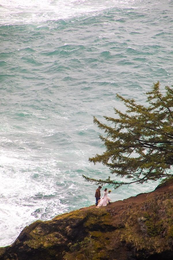 couple standing by a waterfall in wedding attire on Oregon coast