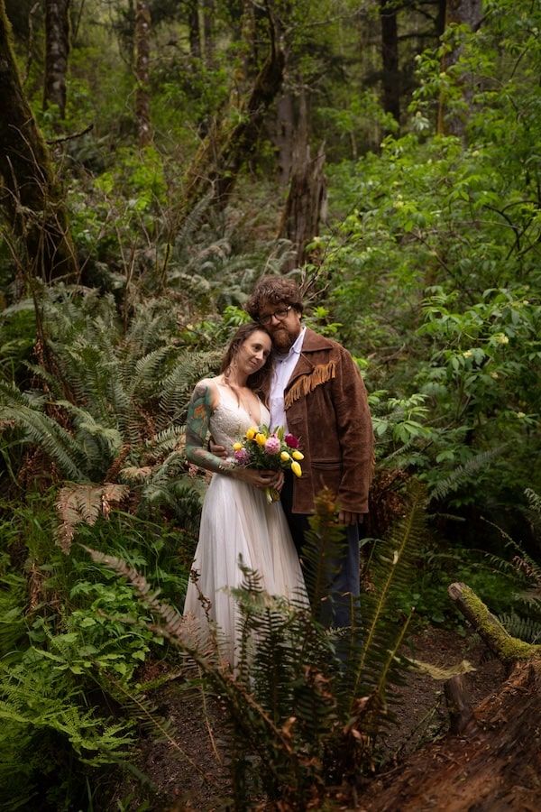couple standing by a waterfall in wedding attire on Oregon coast