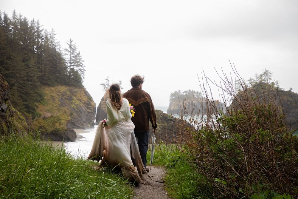 couple standing by a waterfall in wedding attire on Oregon coast