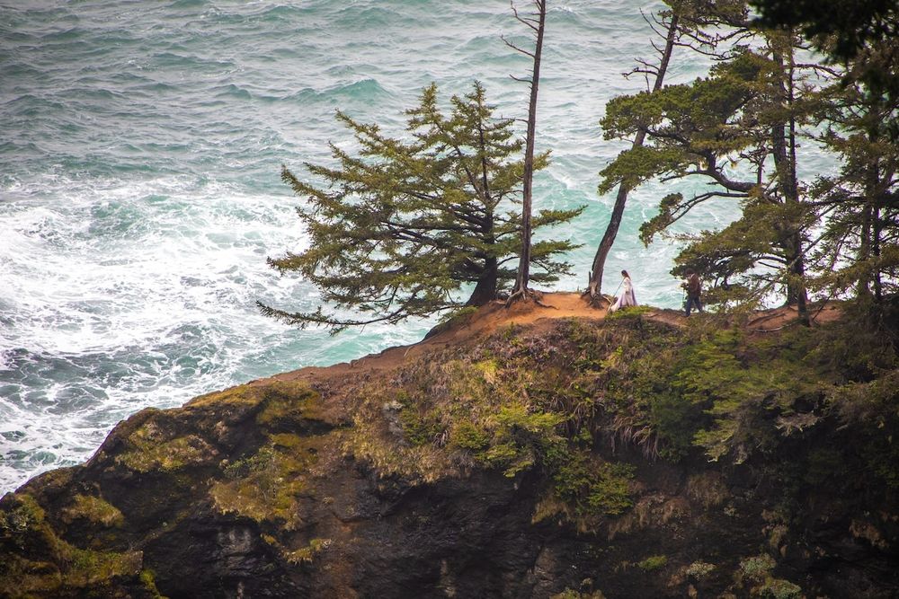 couple standing by a waterfall in wedding attire on Oregon coast
